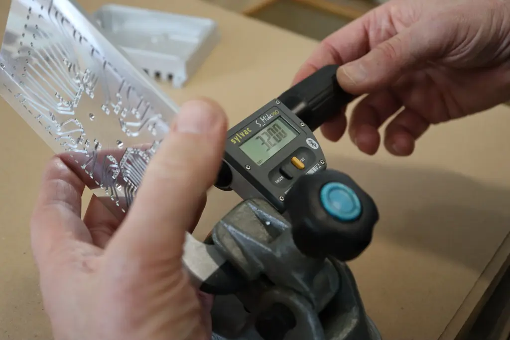Qualitätskontrolle von Hand, Messen eines gefrästen Präzisionsteils mit dem Mikrometer